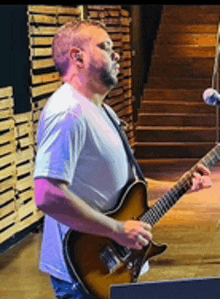 a man in a white shirt is playing a guitar on a stage