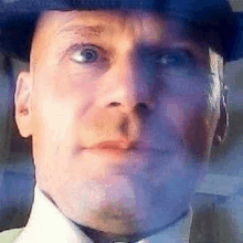 a close up of a man wearing a hat and a tie .