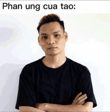 a man stands with his arms crossed in front of a white wall with the words phan ung cua tao written above him