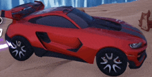 a red sports car with black wheels is parked in the sand