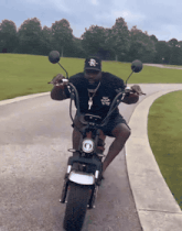 a man wearing a black hat with the letter r on it is riding a motorcycle