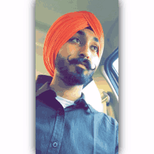 a man with a beard wearing an orange turban and a black shirt