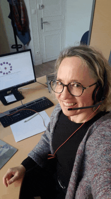 a woman wearing a headset is smiling in front of a computer monitor