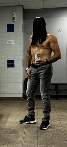 a shirtless man takes a selfie in a locker room