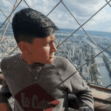 a young boy is sitting on a balcony overlooking a city and a river .