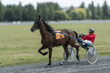 a man in a red jacket is riding a brown horse with the number 2 on the back