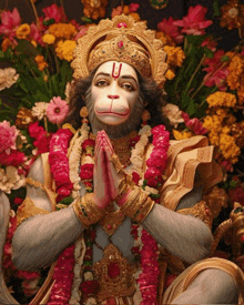 a statue of a monkey with a red u on his forehead is surrounded by flowers