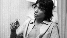 a young man is smoking a cigarette in a black and white photo .