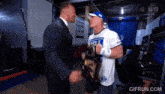 a man in a suit is shaking hands with a man in a white shirt that says ' rapp arena '