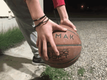 a person is holding a basketball that says " mak " on it