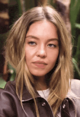 a close up of a woman 's face wearing a brown leather jacket