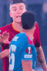 a man in a blue jersey with the number 5 on it is hugging another man in a red shirt