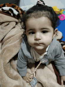 a baby girl is laying on a blanket with a pacifier in her hand