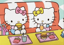 two hello kitty characters are sitting on a couch eating hamburgers