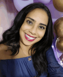 a woman wearing a blue off the shoulder top smiles for the camera