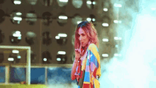 a woman in a colorful sweater stands in front of a building