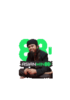 a man with long hair and a beard sits in front of a green sign that says asianwin88