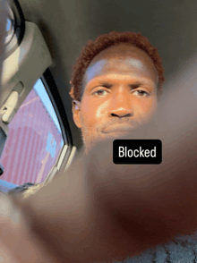 a man in a car with a sticker on his face that says " blocked "