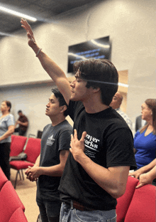 a man wearing a black shirt that says prayer works holds up his hand