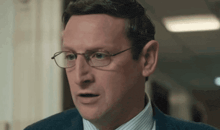 a man wearing glasses and a suit is making a face