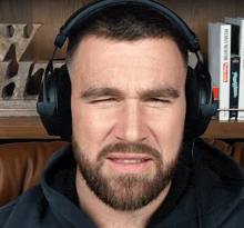 a man wearing headphones is looking at the camera with a book behind him that says ' benjamin newton ' on it