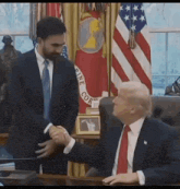 a man in a suit and tie is shaking hands with a man in a suit and tie while sitting at a desk .