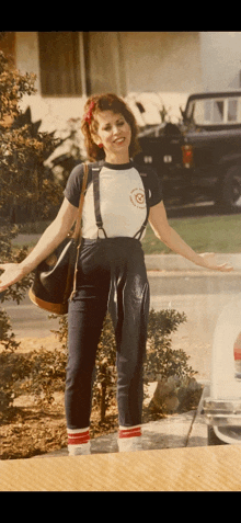 a woman wearing suspenders and a t-shirt with a circle on it