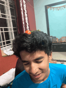 a boy in a blue shirt has a small orange on his head