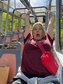 a woman wearing a maroon shirt that says ' ucsd ' on it is sitting on a bus