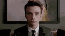 a man in a suit and tie is looking at the camera .