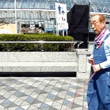 a man wearing overalls is walking a dog on a leash in front of a sign pointing to the right