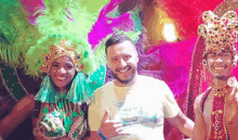 a man is giving a thumbs up while posing for a picture with two women in colorful costumes .