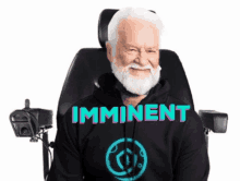 an elderly man with a beard is sitting in a wheelchair wearing a hoodie that says imminent .