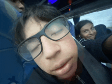 a boy wearing glasses is taking a selfie in a blue bus