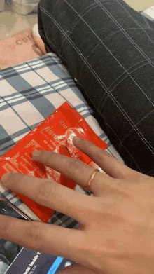 a person laying on a bed holding a red packet that says ' i 'm ' on it