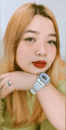 a woman wearing a watch and red lipstick is taking a selfie .