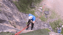 a man wearing a blue shirt and a white helmet is climbing a rock wall with manuel el mundo written on the bottom