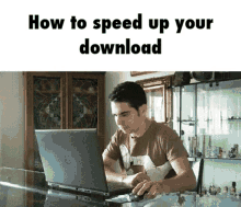 a man is sitting at a table using a laptop computer with the words how to speed up your download above him