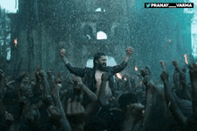a man stands in front of a crowd with his arms in the air and the words pranay_varma behind him