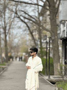 a man wearing sunglasses and a white shirt is standing on a street