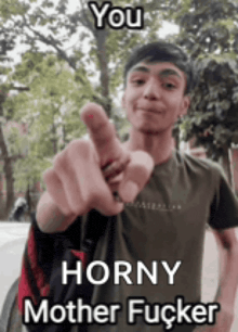 a young man is pointing at the camera while wearing a green shirt .