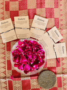 a bowl of rose petals sits on a table next to a stack of cards that say sisters