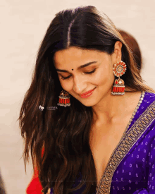 a close up of a woman wearing earrings and a purple shirt