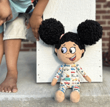 a stuffed doll with curly hair is wearing a pajama with trucks on it