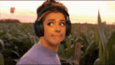 a woman wearing headphones and a microphone makes a face in a field