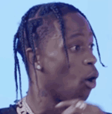 a close up of a man 's face with braids and a tattoo on his neck .