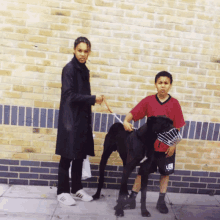 a boy wearing a red shirt with the letter u on it stands next to a woman holding a dog