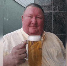 a man is holding a glass of beer in his hand .