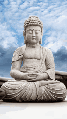 a statue of a buddha is sitting in front of a cloudy sky