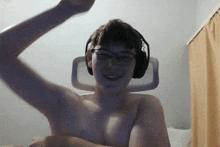 a shirtless man wearing glasses and headphones flexes his arm